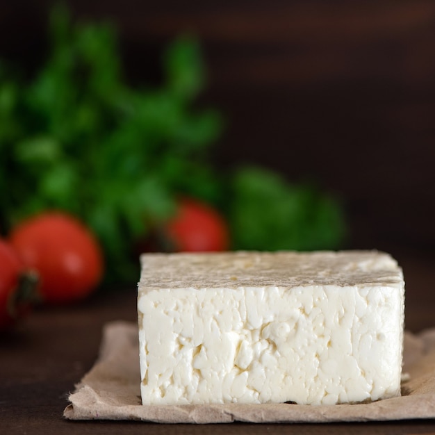 Grande pezzo di formaggio feta sul tavolo di legno scuro.