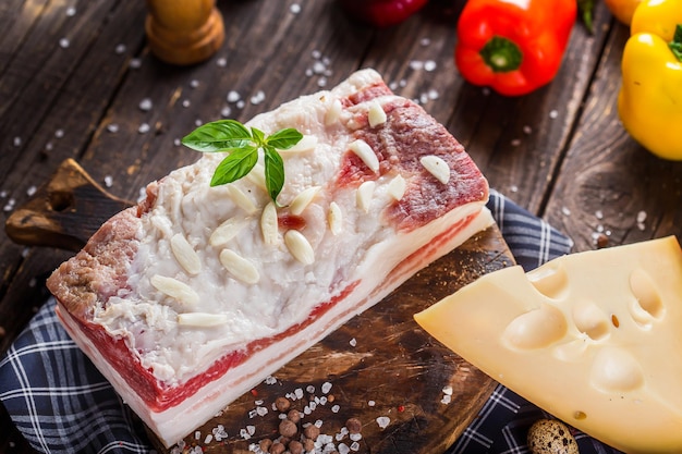 Pezzo grosso, strutto fresco lardo di maiale al sale, su un tagliere da cucina, formaggio a pasta dura scuro e lunatico,