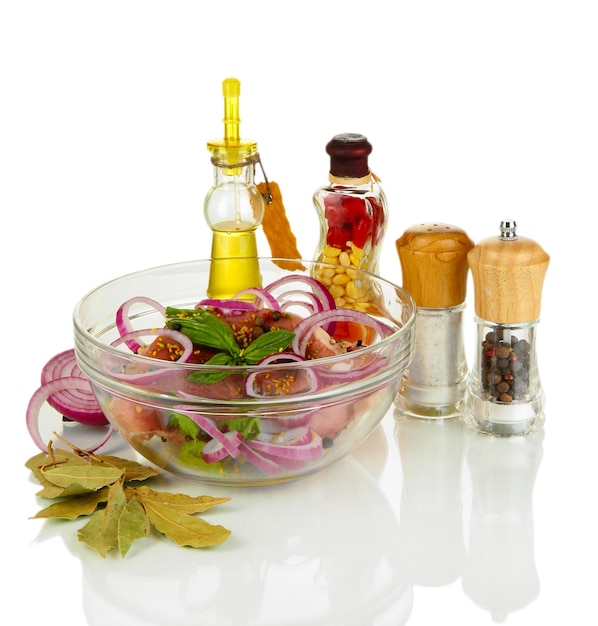 A large piece of pork marinated in bowl with herbs spices and cooking oil isolated on white