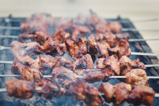 Photo large pieces of meat on a skewer are cooked on the grill