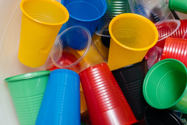 A large pile of multicolored plastic cups scattered on the floor. Pollution of the environment by human waste