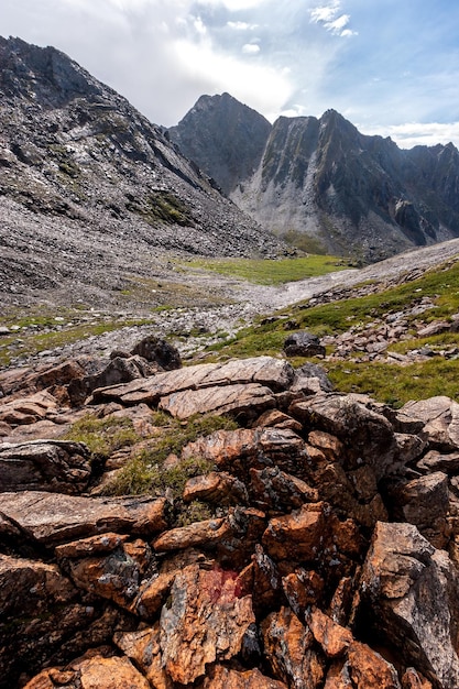 A large pile of red rock stones in the foreground and mountains in the background Clouds in the sky Vertical