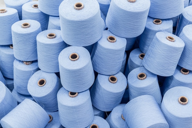 A large pile of spools of blue thread. close up