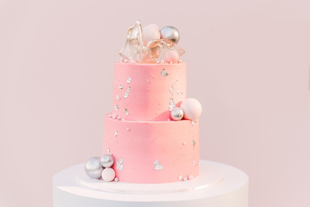 A large pink cake with a pink photo zone of silver balloons on the background. Party decorated with balloons