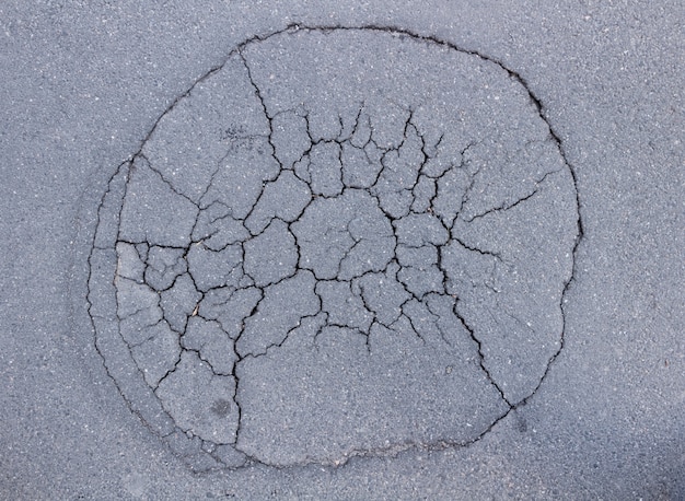 A large pit in the asphalt with cracks