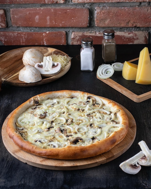 きのこと玉ねぎの大きなピザと食材のレストランが付いている木製のテーブル