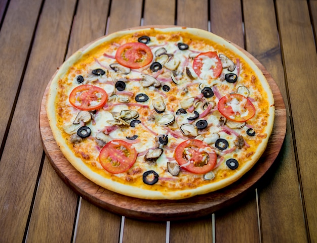 Large pizza on a wooden table.