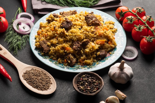 Photo a large plate filled with pilaf next to cherry tomatoes fresh pepper  garlic zeros and a mixture