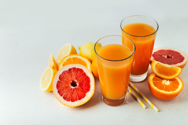 Large plvn on a glass of juice with citrus fruits orange lemon and grapefruit on a white table