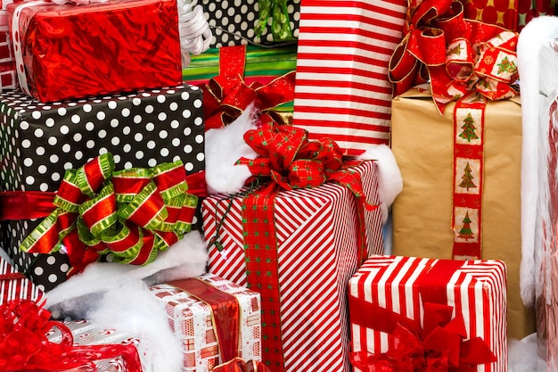 Large presents wrapped in colorful papers with bows in a pile ready for Christmas.