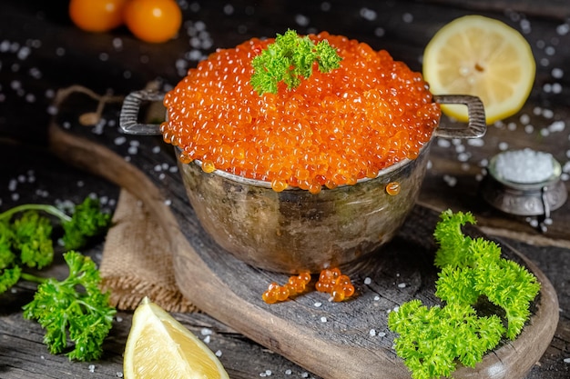 소박한 빈티지 스타일의 큰 빨간 캐비어, 나무 커팅 보드에 양동이 소스 팬의 깊은 그릇