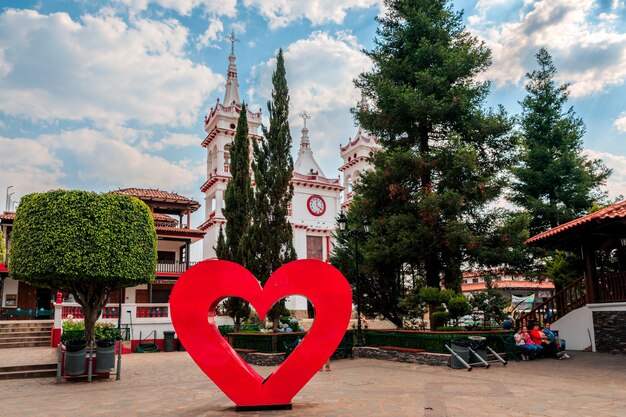 A large red heart on a square with benches and trees