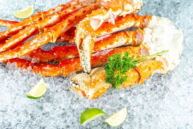 Large red kamchatka crab claws phalanx legs tentacles, lies on ice, cherry, slices of lemon and lime