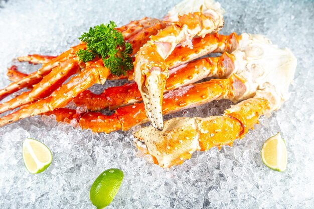 Large red kamchatka crab claws phalanx legs tentacles, lies on ice, cherry, slices of lemon and lime