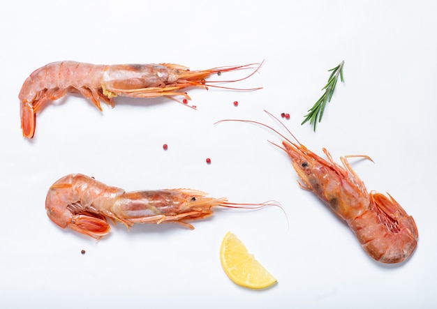 Large red shrimps and lemon with rosemary on a white surface