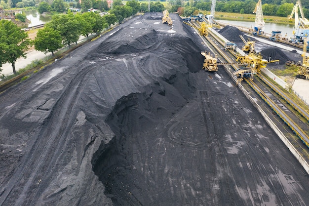 Large reserves of coal at a power plant, many cranes unloading coal, a lot of coal, top view