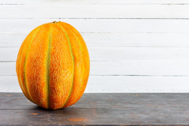 Grande melone giallo maturo su un tavolo di legno nero su sfondo bianco