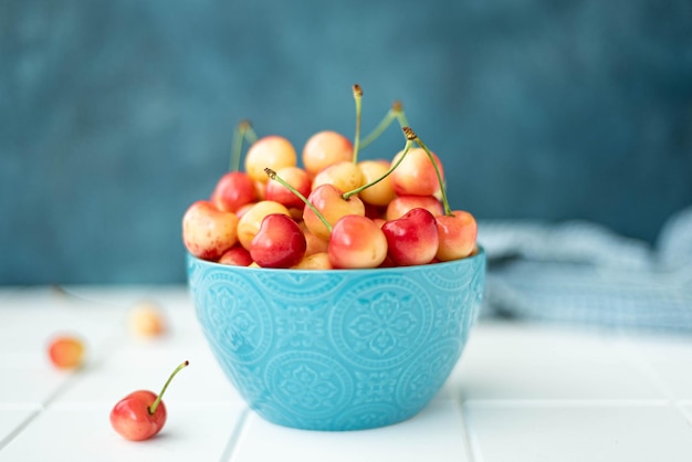 Photo large ripe yellow pink cherries in a blue bowl