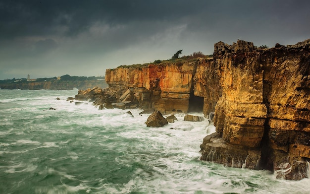 a large rock formation with a cave in the middle of the ocean