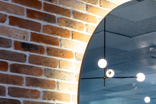 A large round illuminated mirror hangs on a brick wall in the restaurant Interior design in a stylish cafe or bar