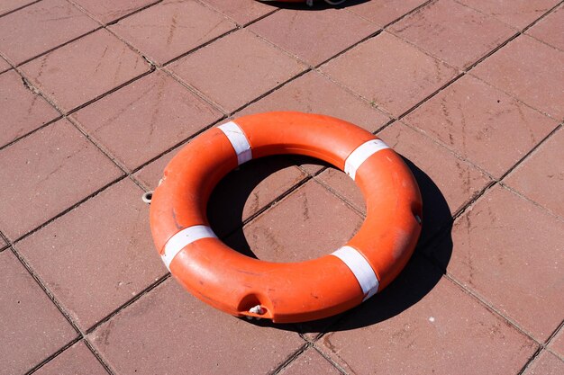 Photo a large round orange plastic life ring for safety and rescue people in the water lies on the stone
