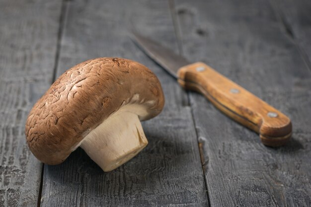 A large Royal champagne and a knife on a black wooden table. Vegetarian food. Artificially grown mushrooms.