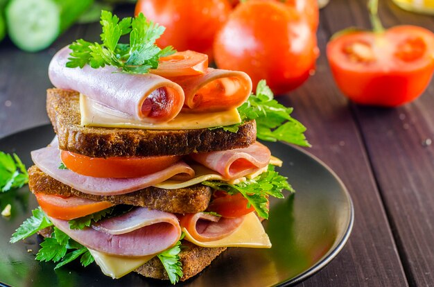 Large sandwich with sausage and cheese, cucumber and tomato