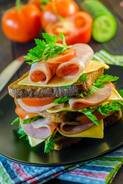 Large sandwich with sausage and cheese, cucumber and tomato