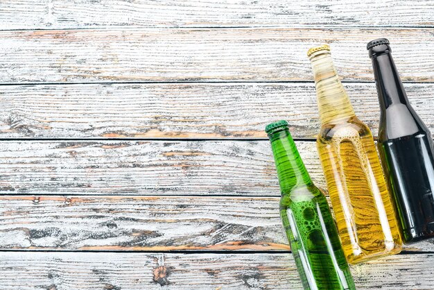 A large selection of beer bottles On a white wooden table Free space for text Top view