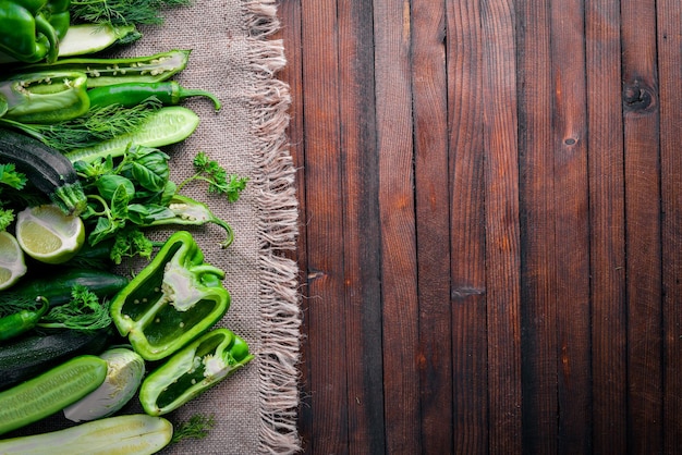 A large set of green vegetables on a wooden background. Top view. Free space.