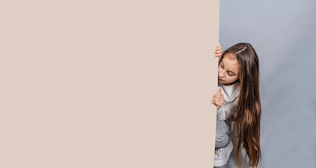 Photo large sheet of white cardboard llittle girl and empty banner advertising