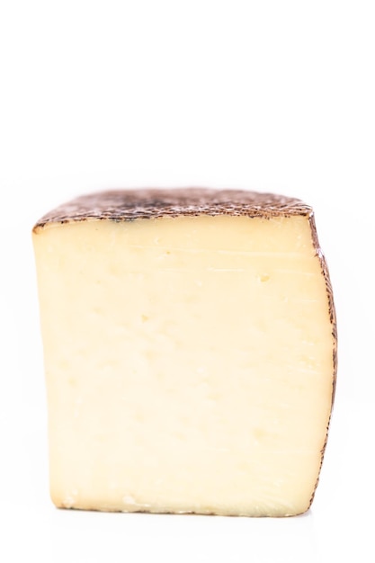 Large slice of aged Manchego cheese on a white background.