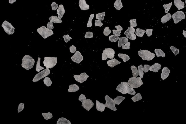 Photo large and small crystals of rock salt on a black background.