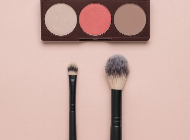 Large and small makeup brushes and a set of face shadows Flat lay