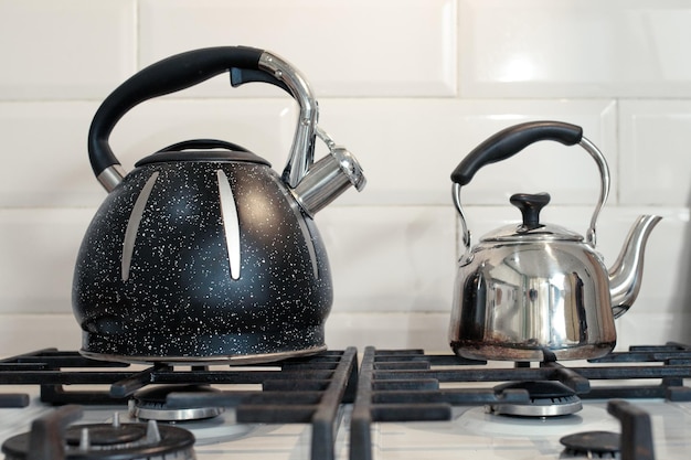 Large and small metal teapot on a gas stove