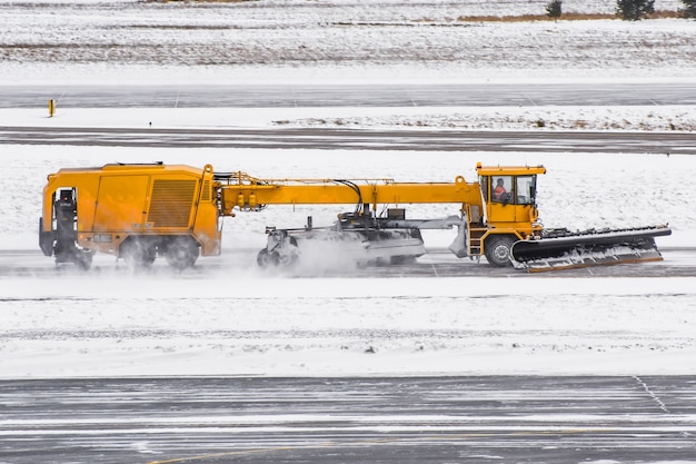 Large snow plowing machine at work on the road during a snow storm in winter.