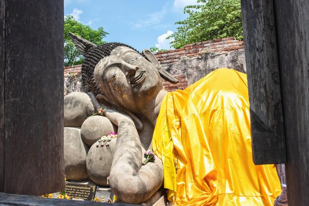 A large statue of reclining buddha with yellow robe in Ayutthaya province Thailand