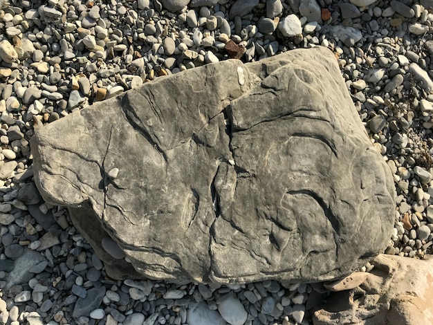 A large stone lies on a sea pebble on the beach. piece of rock. High quality photo