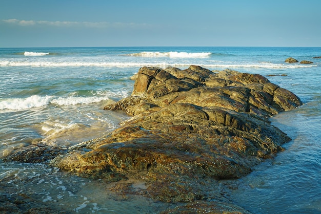 Foto una grossa pietra nell'acqua vicino all'oceano