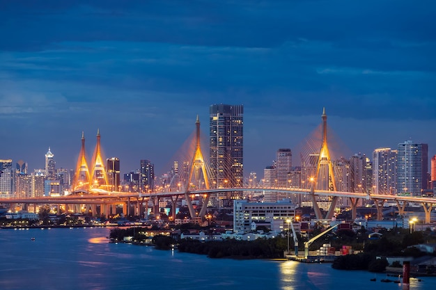 Large suspension bridge over Chao Phraya river at twilight with city in background