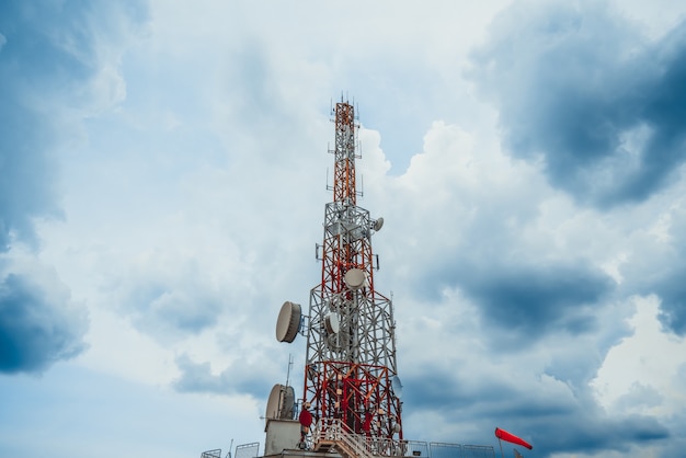 Large telecommunication tower against sky and clouds in background