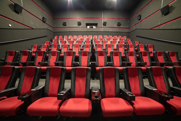 A large theater with red seats and a wall with the words " cinema " on it.