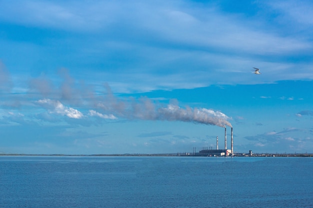 large thermal power plant against the backdrop of a large blue sky and reservoir