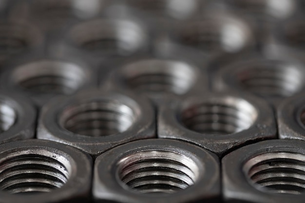 Photo large threaded steel nuts for bolts stacked in a row closeup screw abstract background