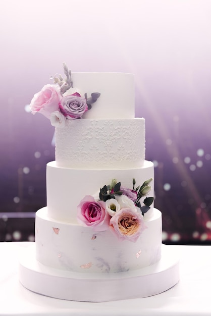 Large tiered white wedding cake with backlit flowers