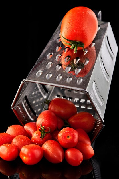 Large tomato on grater with small cherry tomatoes