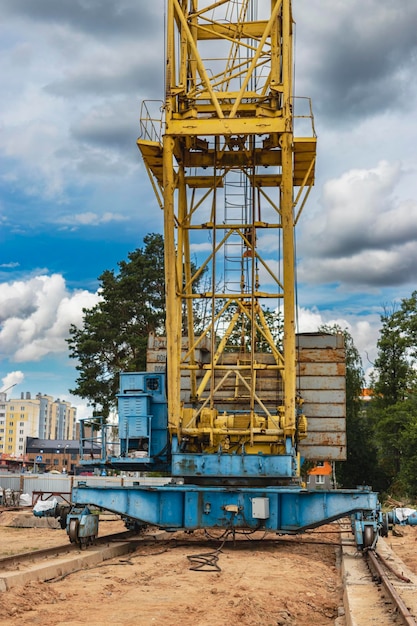 A large tower crane at a construction site against the backdrop of a modern monolithic house Modern housing construction industrial engineering Construction of mortgage housing