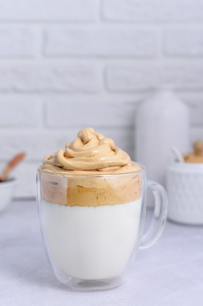 Large transparent mug with dalgona coffee on a light background