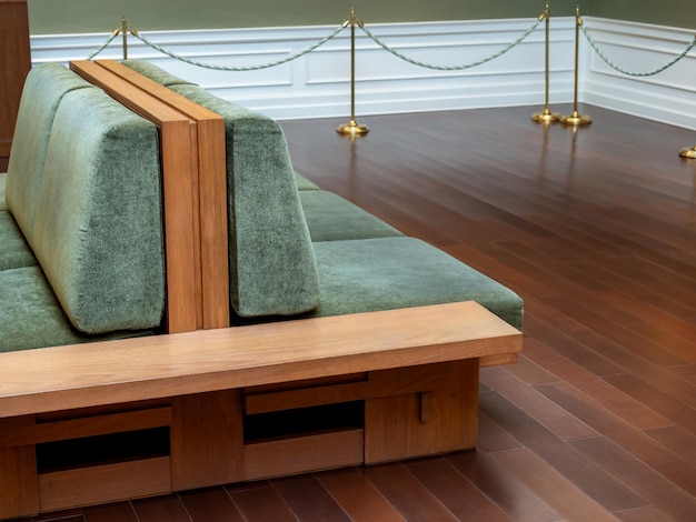 Large twin vintage wooden sofa bench upholstered in green velvet sits in the museum for visitors to rest on Empty big luxury wood seat chair with nobody decoration on wooden floor in the buildings