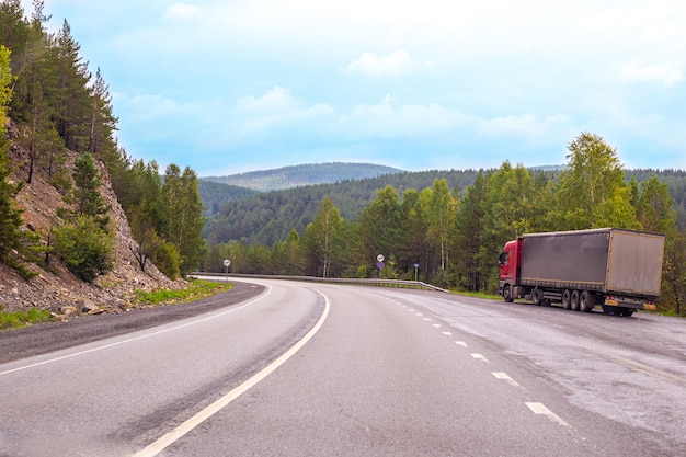 Photo a large van stands on the side of the road among mountains and forests